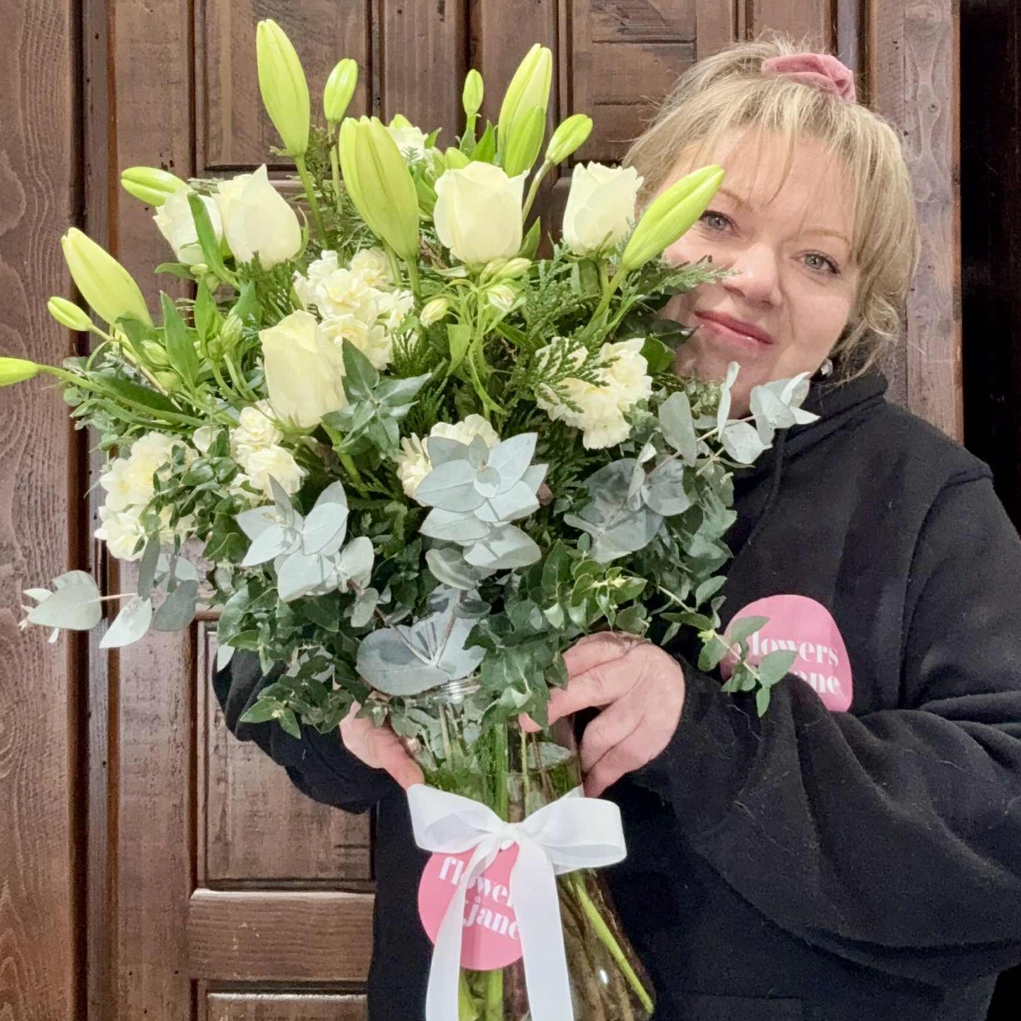 Person holding a bouquet of flowers in front of a wooden cabinet