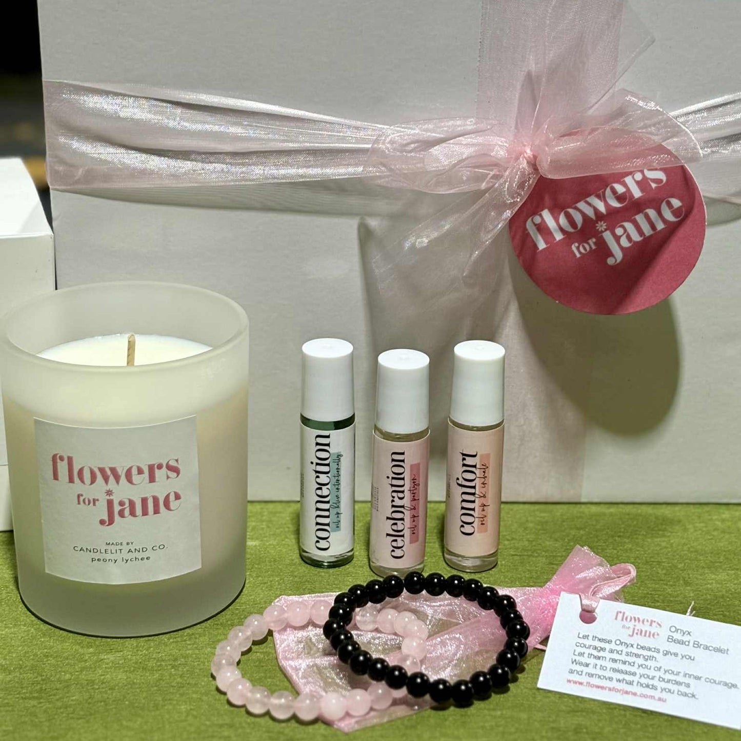 Gift set with candle, bottles, and accessories on a green surface