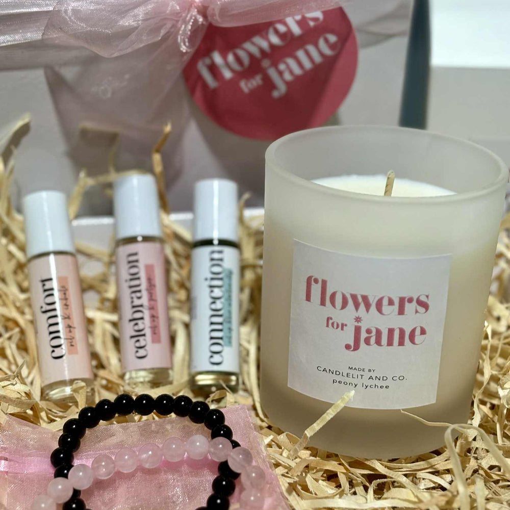 Candle and small bottles with 'flowers for jane' branding on a decorative background.