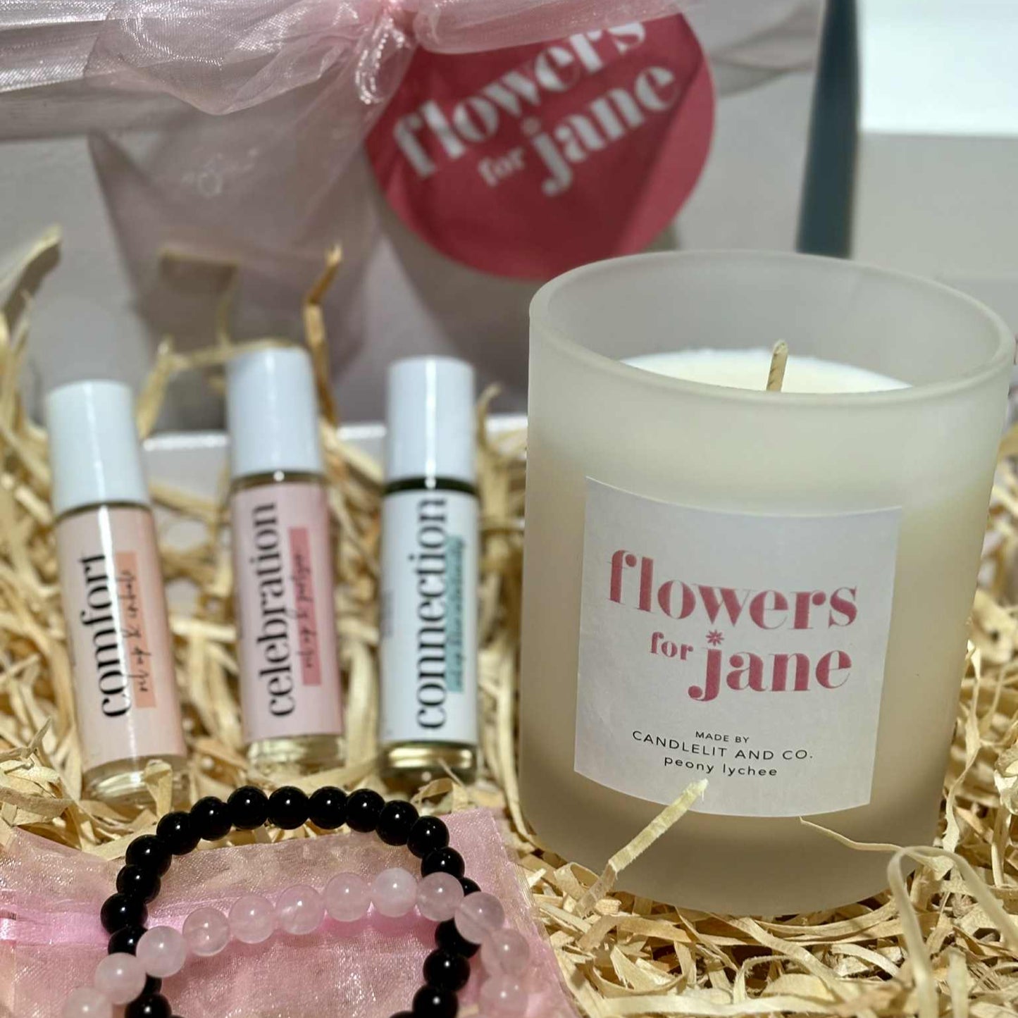 Candle and small bottles with 'flowers for jane' branding on a decorative background.
