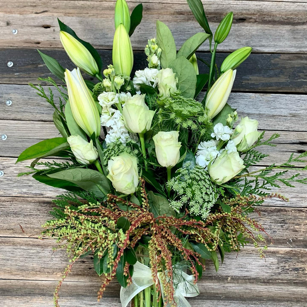 Bouquet of green and white flowers on a wooden surface